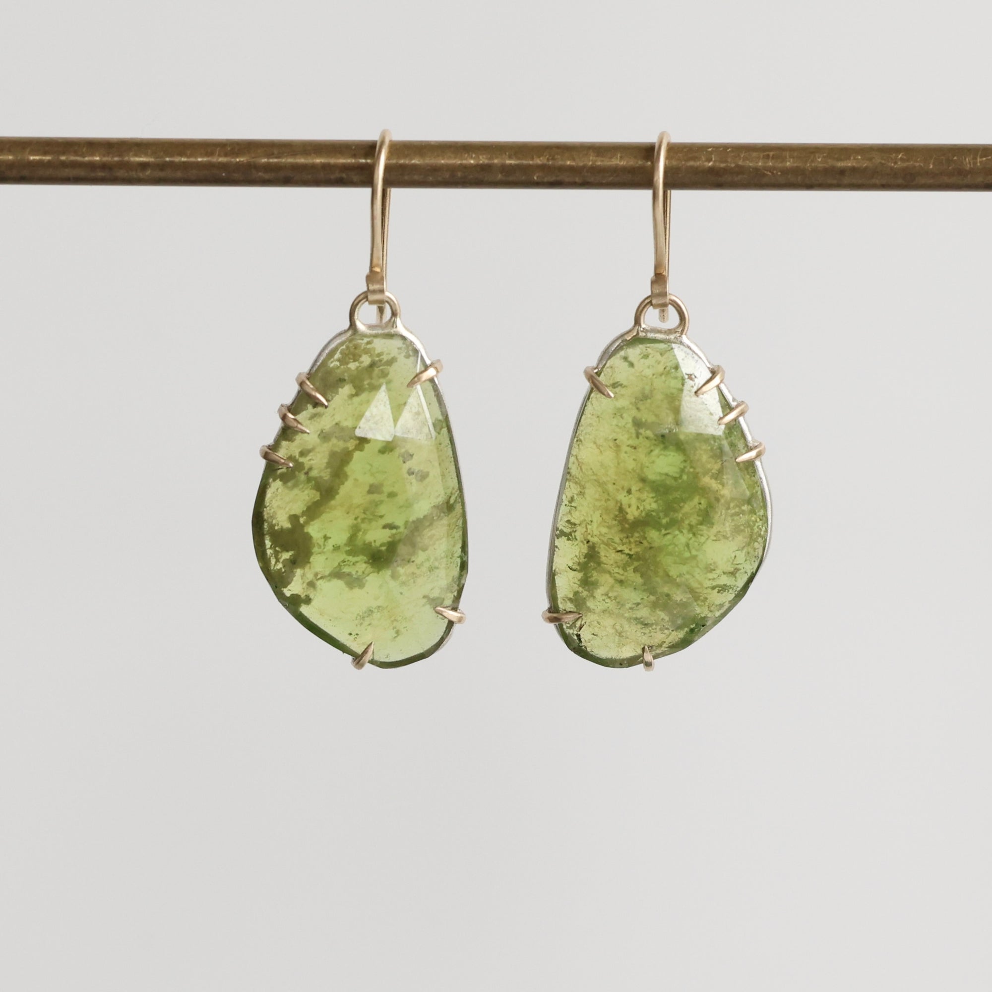 Pair of green teardrop earrings on a gray background