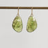 Pair of green teardrop earrings on a gray background
