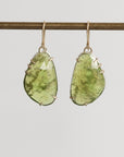Pair of green teardrop earrings on a gray background