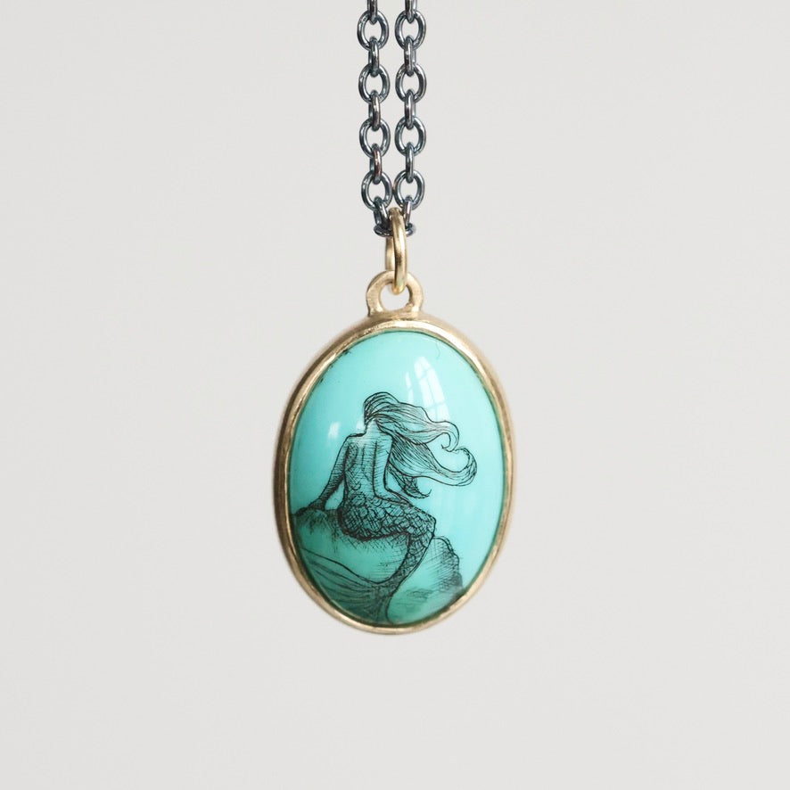 Mermaid pendant necklace on a light gray background
