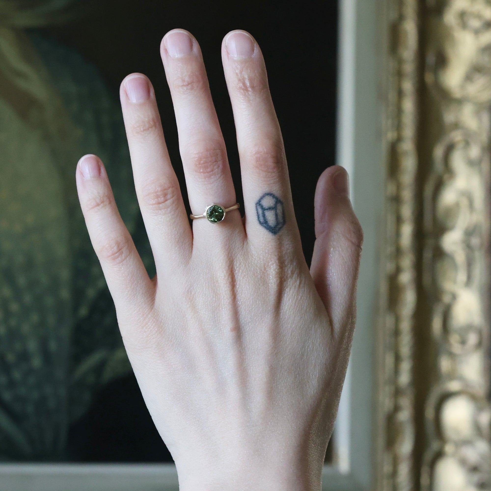 Hand with a ring and tattoo, blurred background