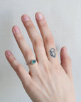 Hand wearing a ring with a blue gemstone on a plain background