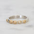Silver ring with gold accents and a diamond on a light gray background