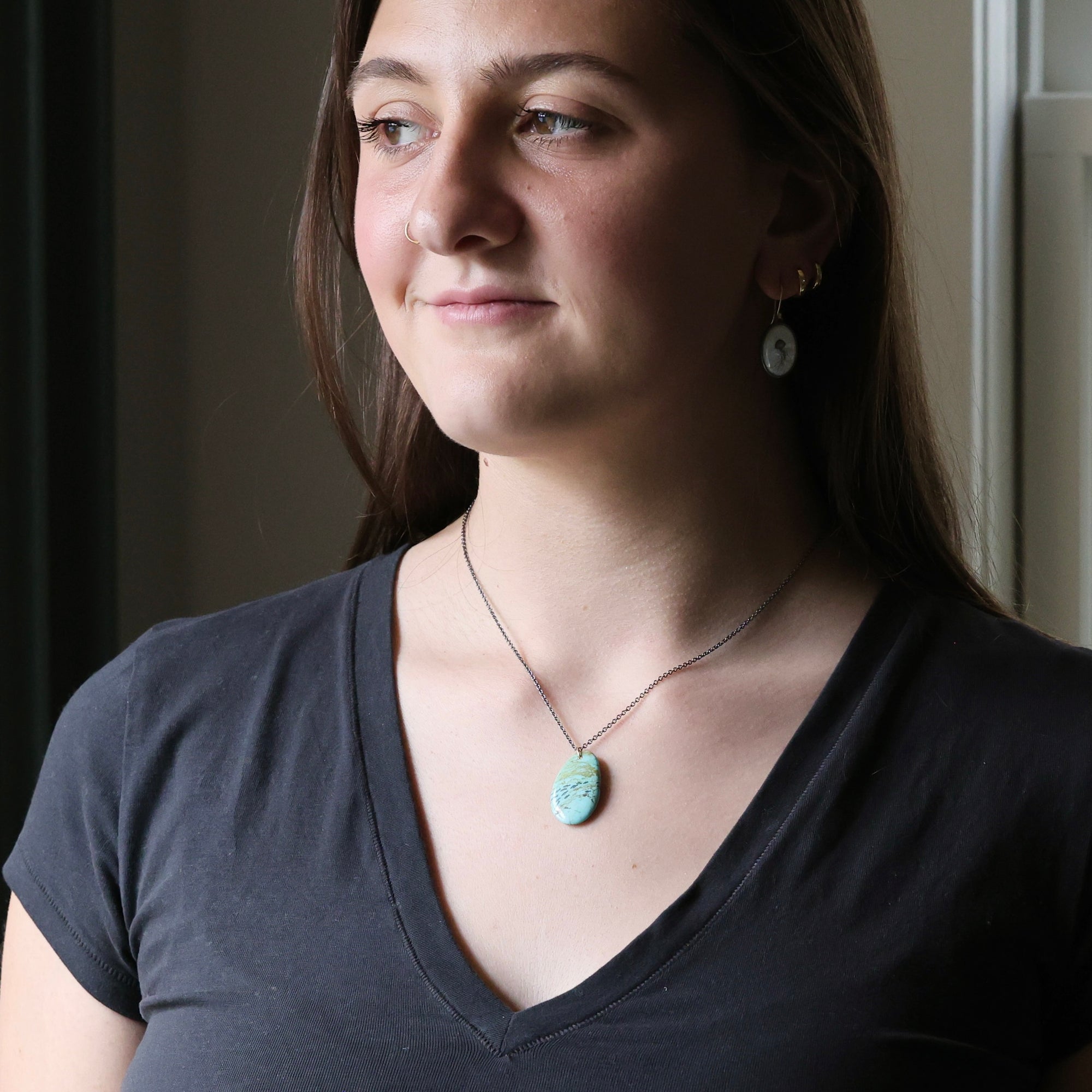 Woman wearing a necklace with a pendant indoors