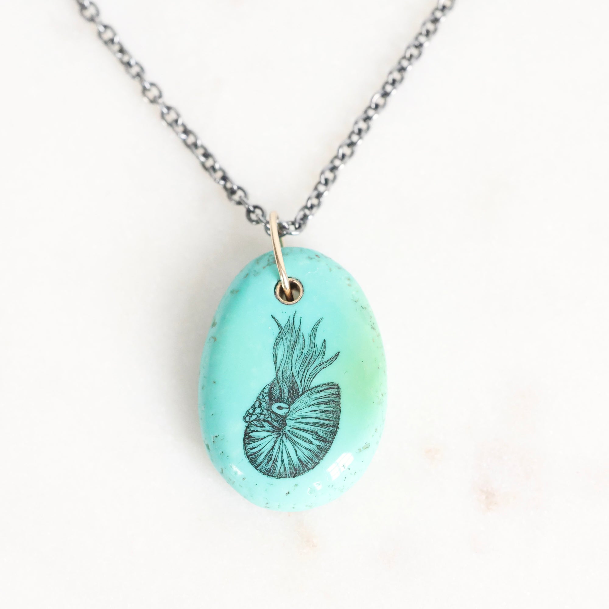 Necklace with a turquoise pendant featuring a black and white design on a white background