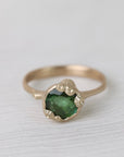 Gold ring with green gemstone on a white background