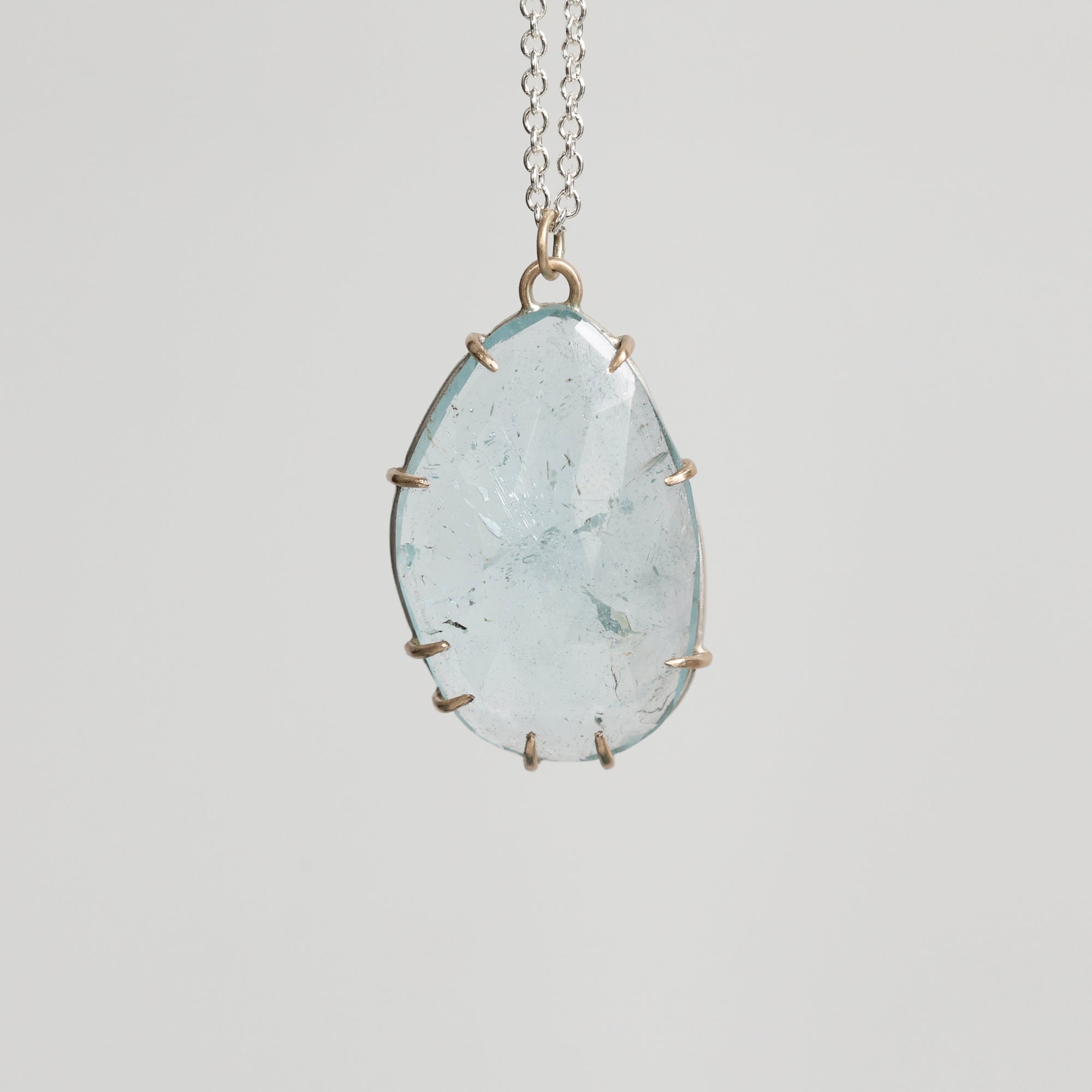 Necklace with a large teardrop-shaped green stone on a light gray background