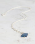 Necklace with a blue pendant on a marble surface