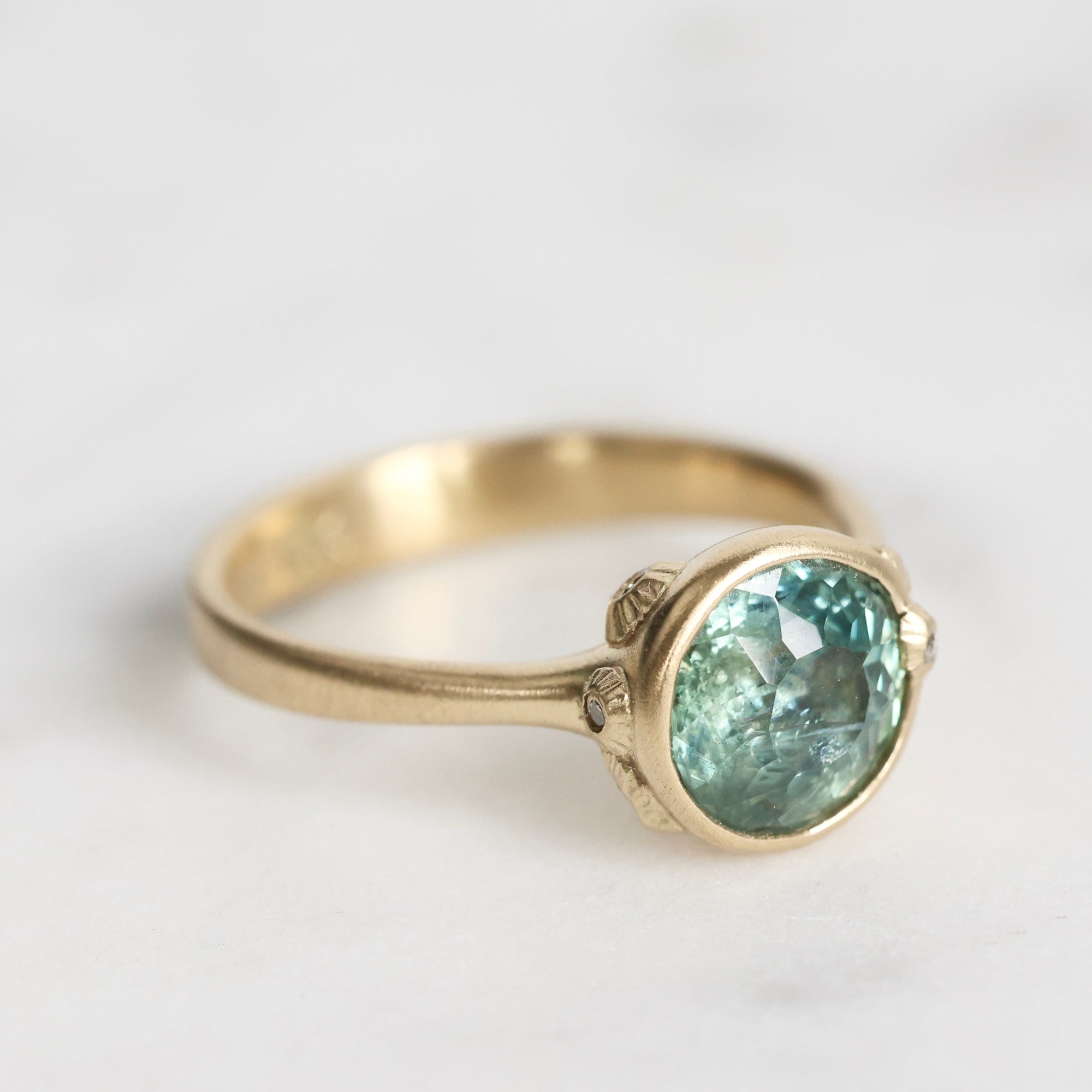 Gold ring with a green gemstone on a light gray background
