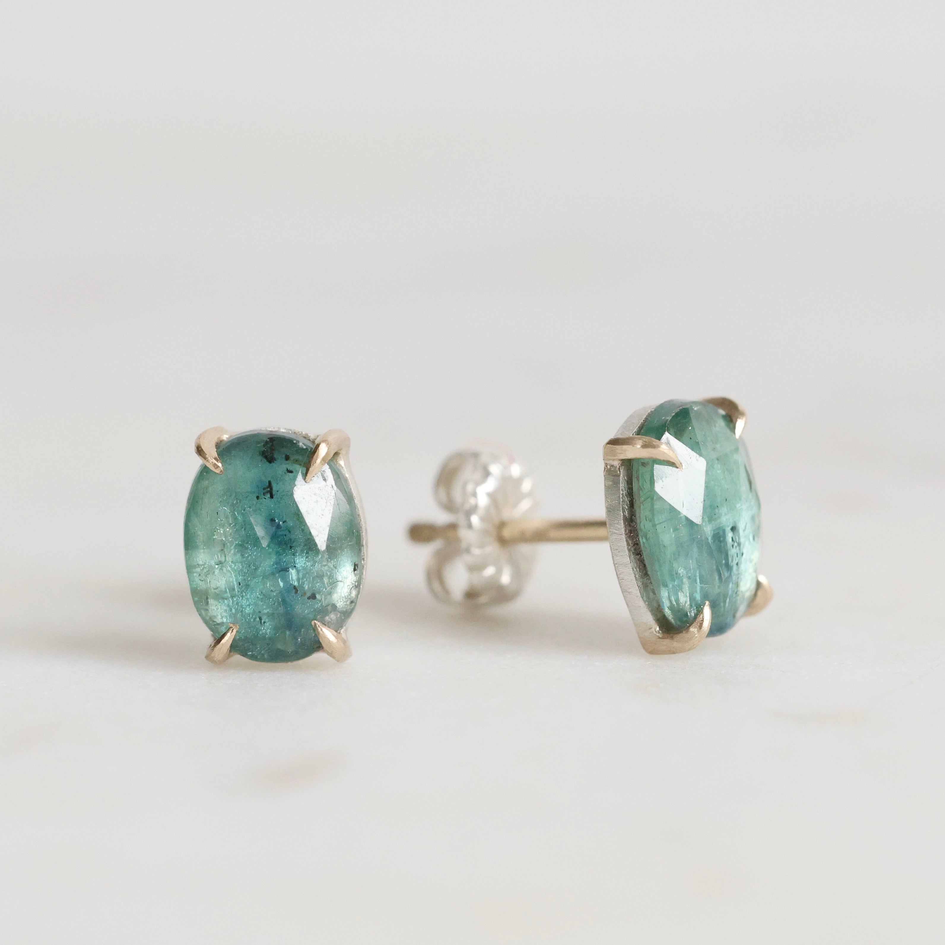 Pair of green gemstone stud earrings on a light gray background