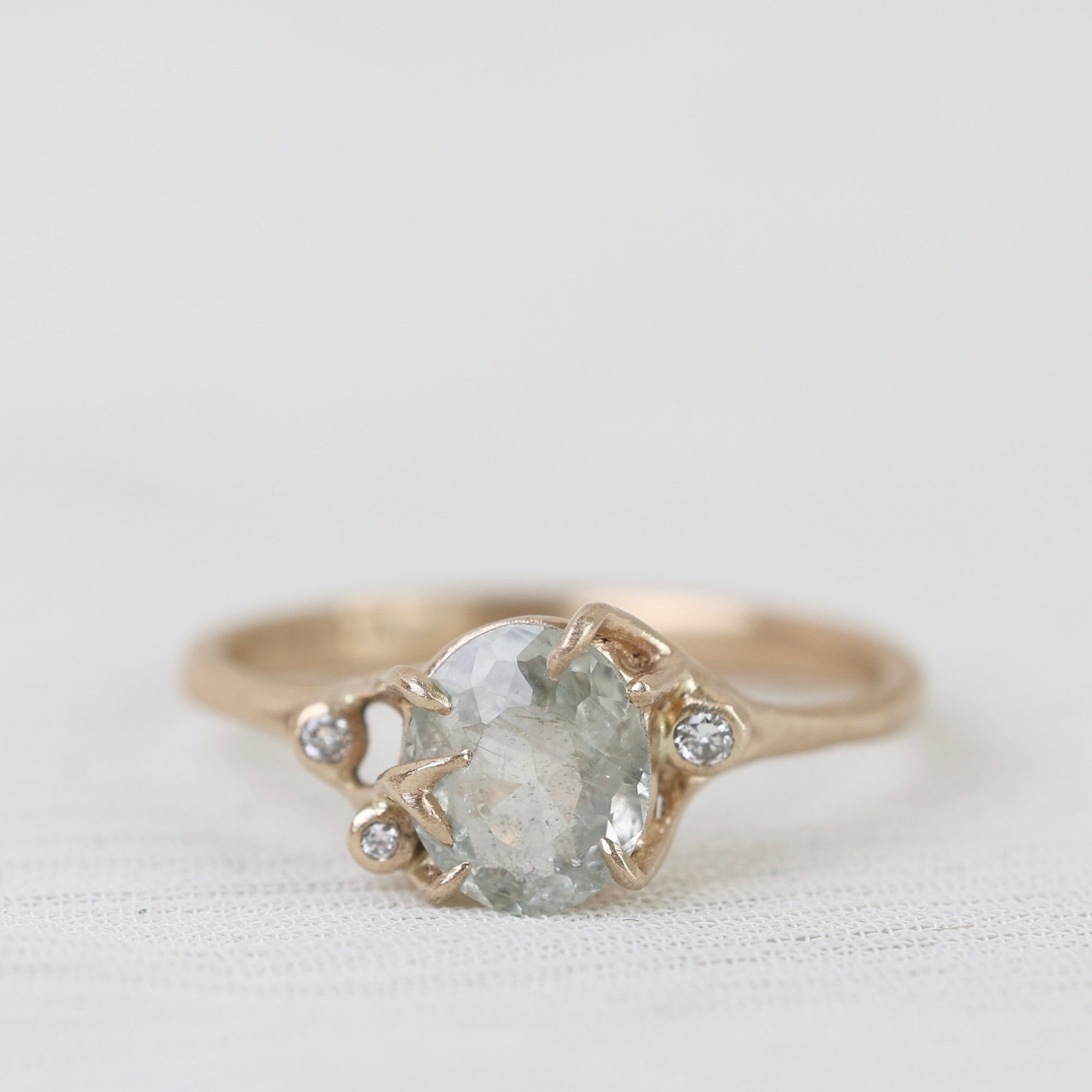 Gold ring with a large central gemstone and smaller stones on a light background