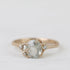 Gold ring with a large central gemstone and smaller stones on a light background