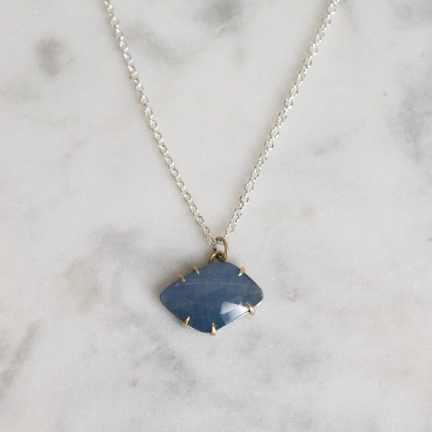 Necklace with a blue pendant on a marble surface
