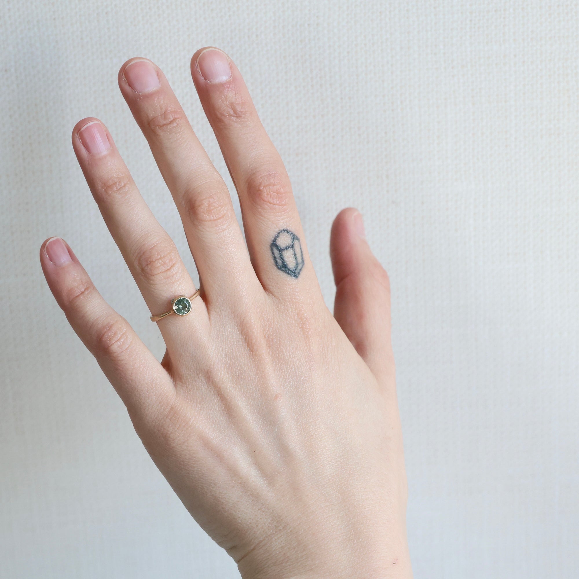 Hand with a ring and tattoo on a plain background
