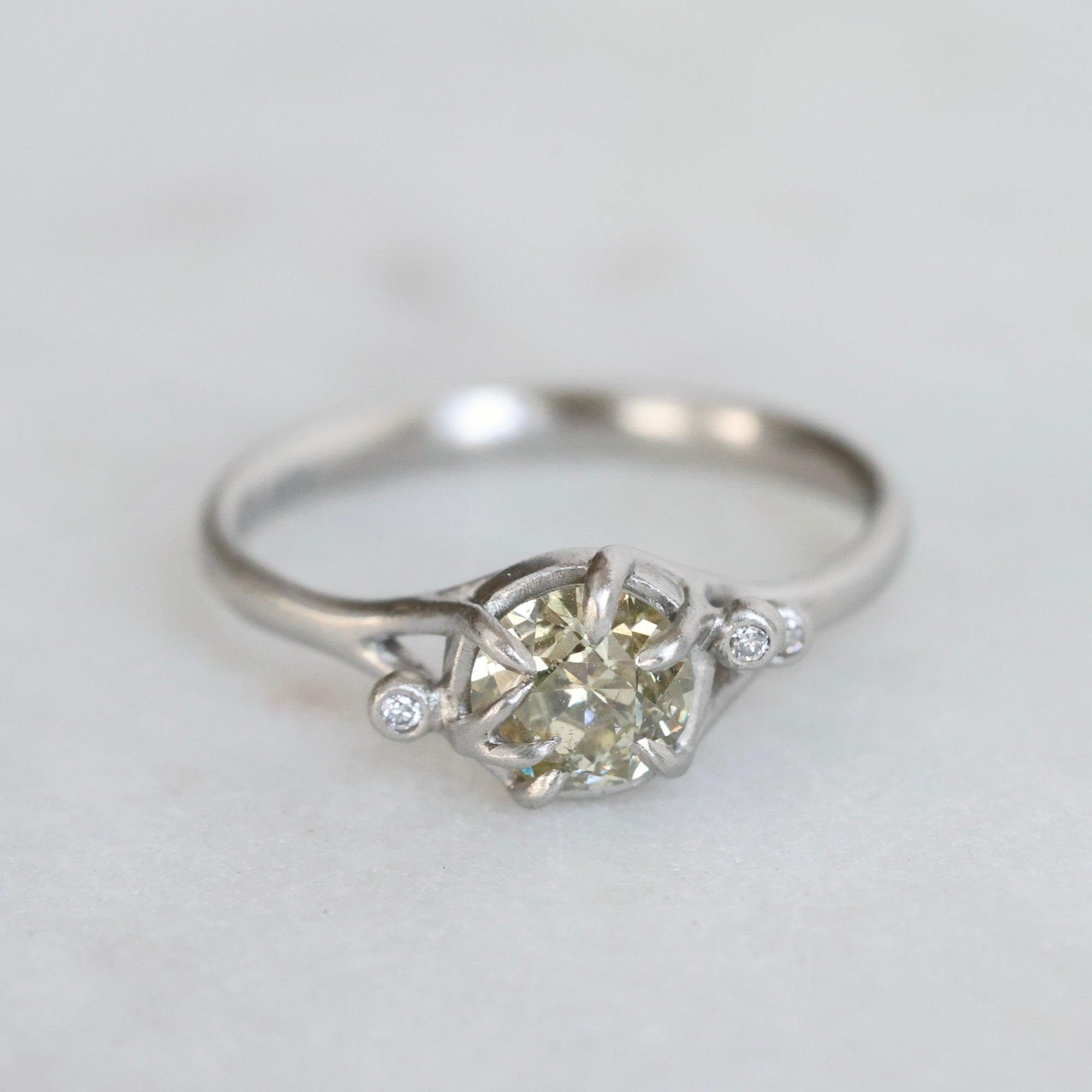 Diamond ring with a heart-shaped center stone on a light gray background