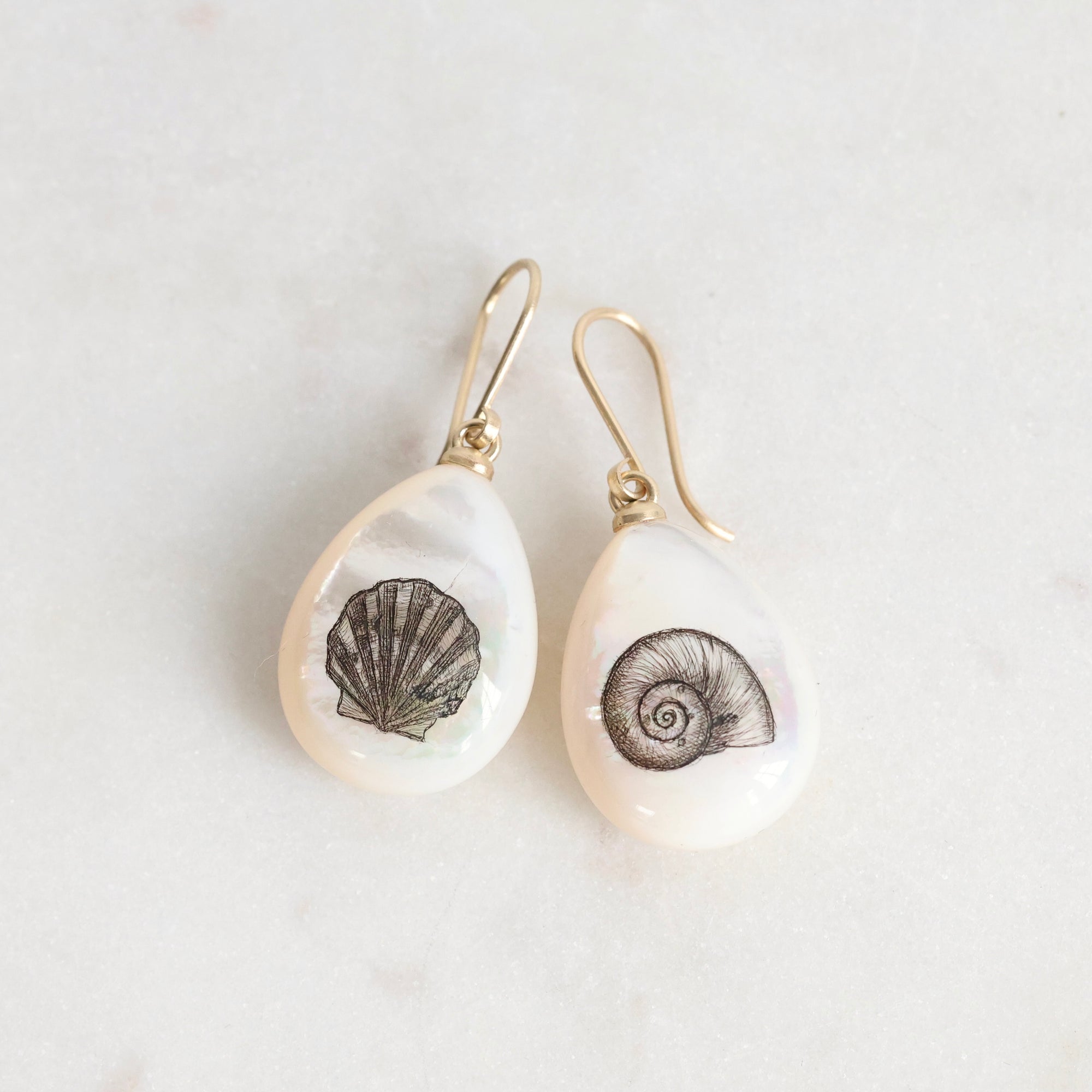 Pair of earrings with shell designs on a light background