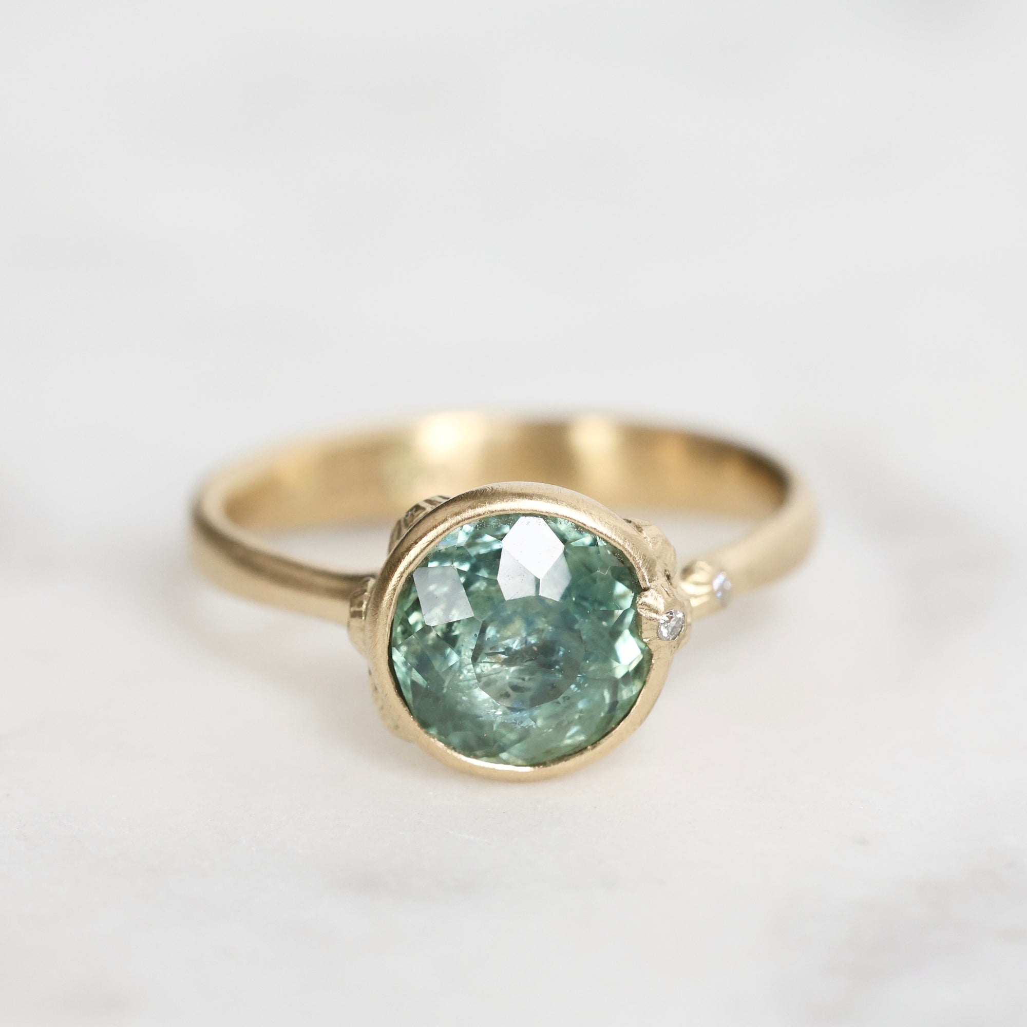 Gold ring with a green gemstone on a light gray background