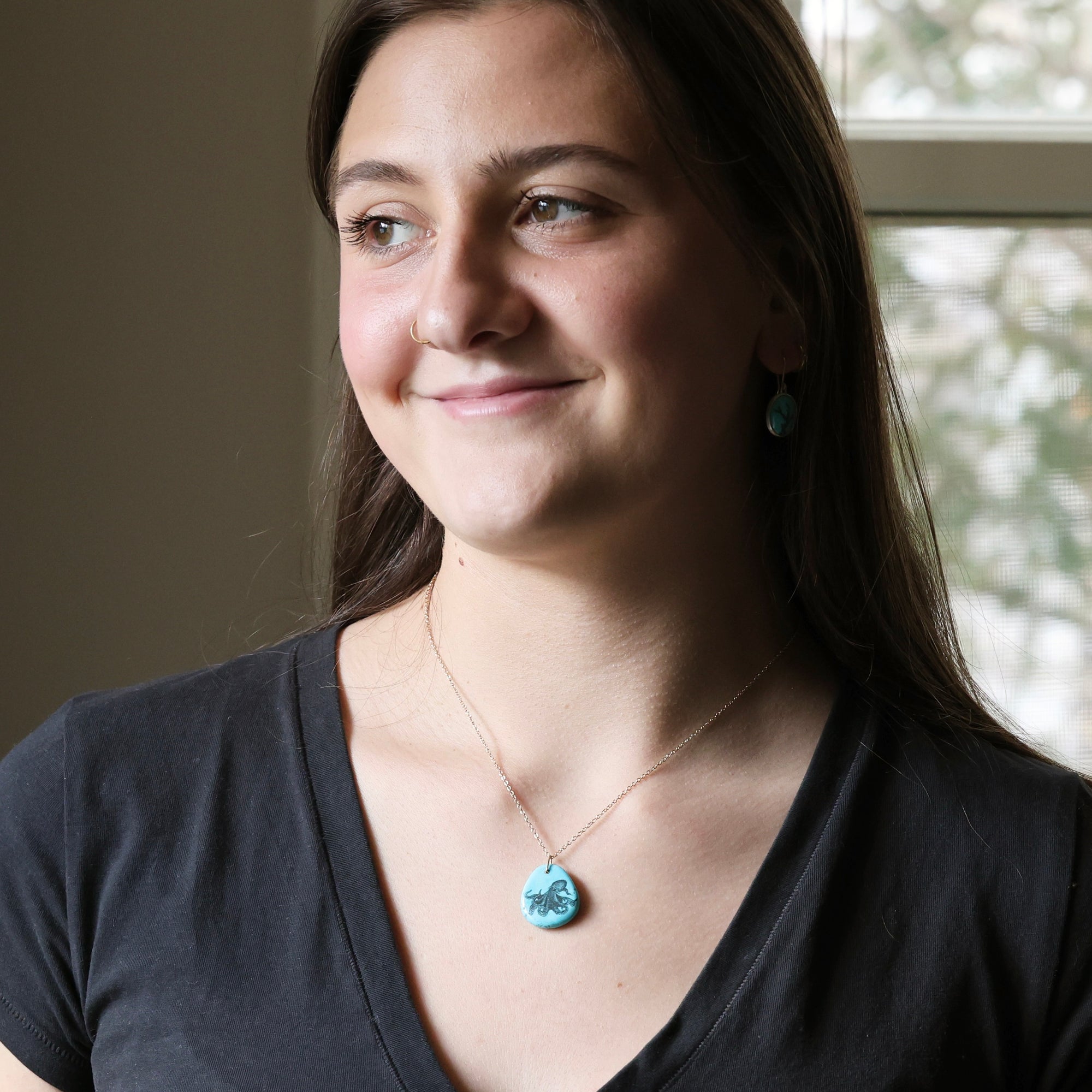 Woman wearing a necklace with a blue pendant indoors