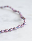 Pearl necklace with purple and pink beads on a light background
