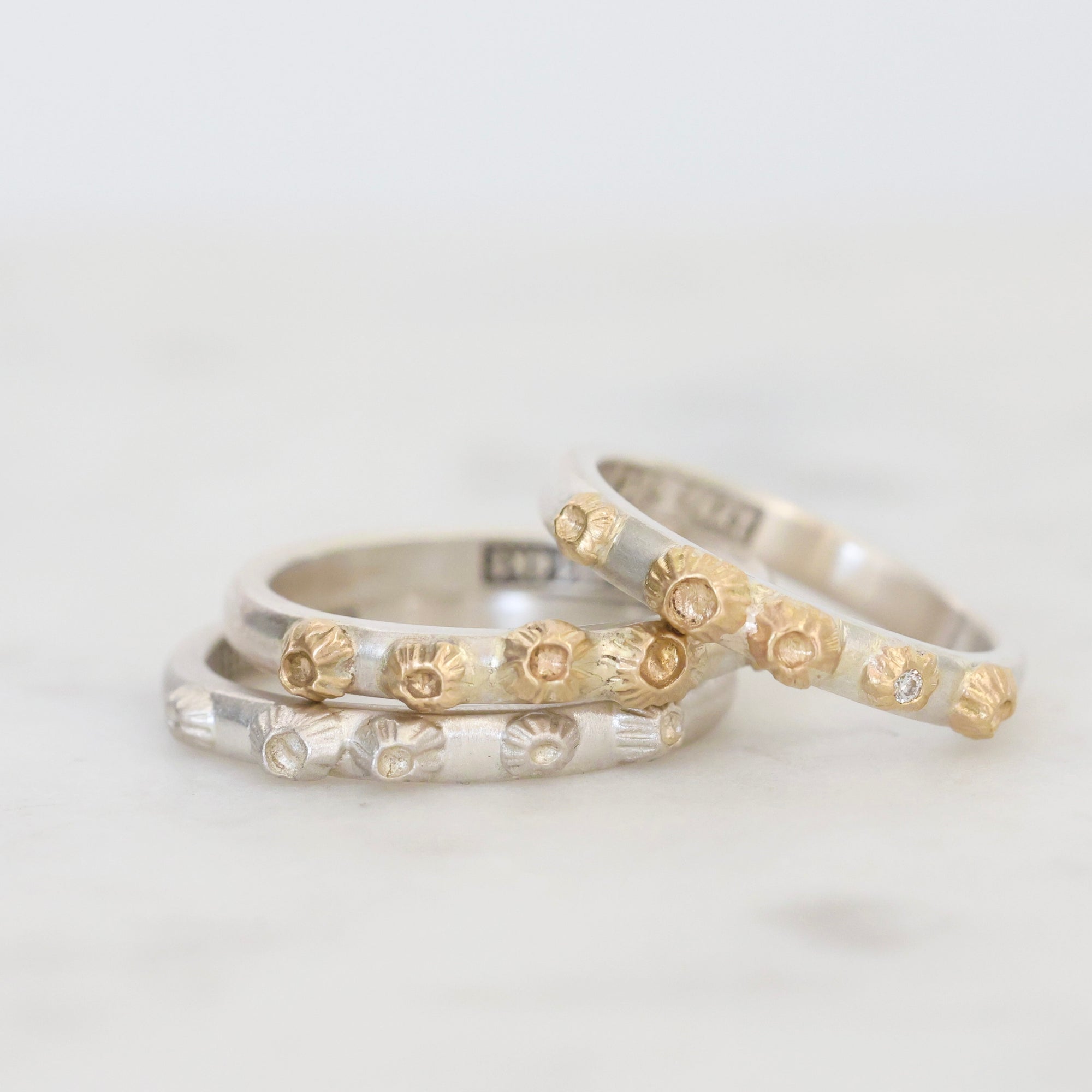 Three silver rings with barnacle designs on a light gray background
