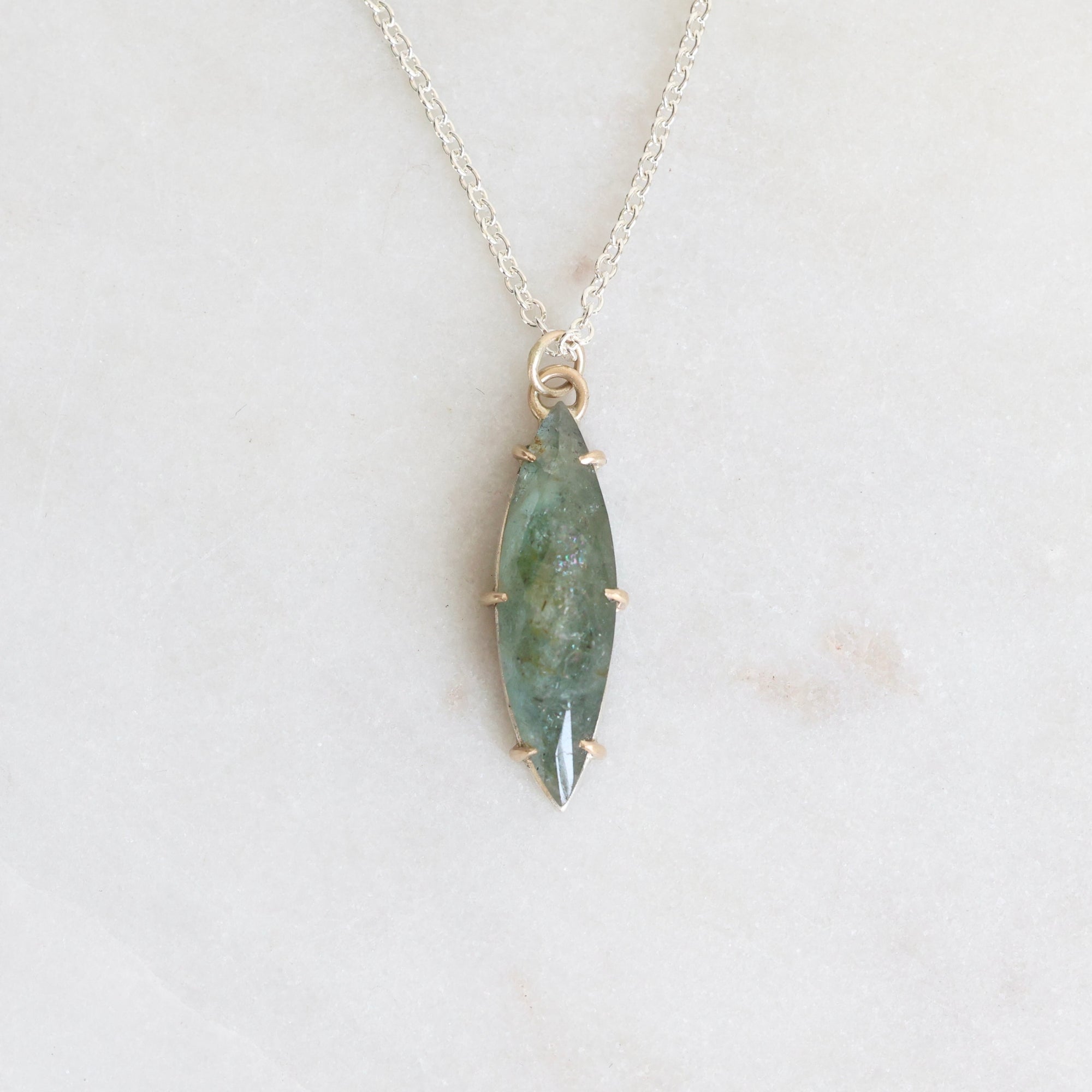 Necklace with a green stone pendant on a light gray background