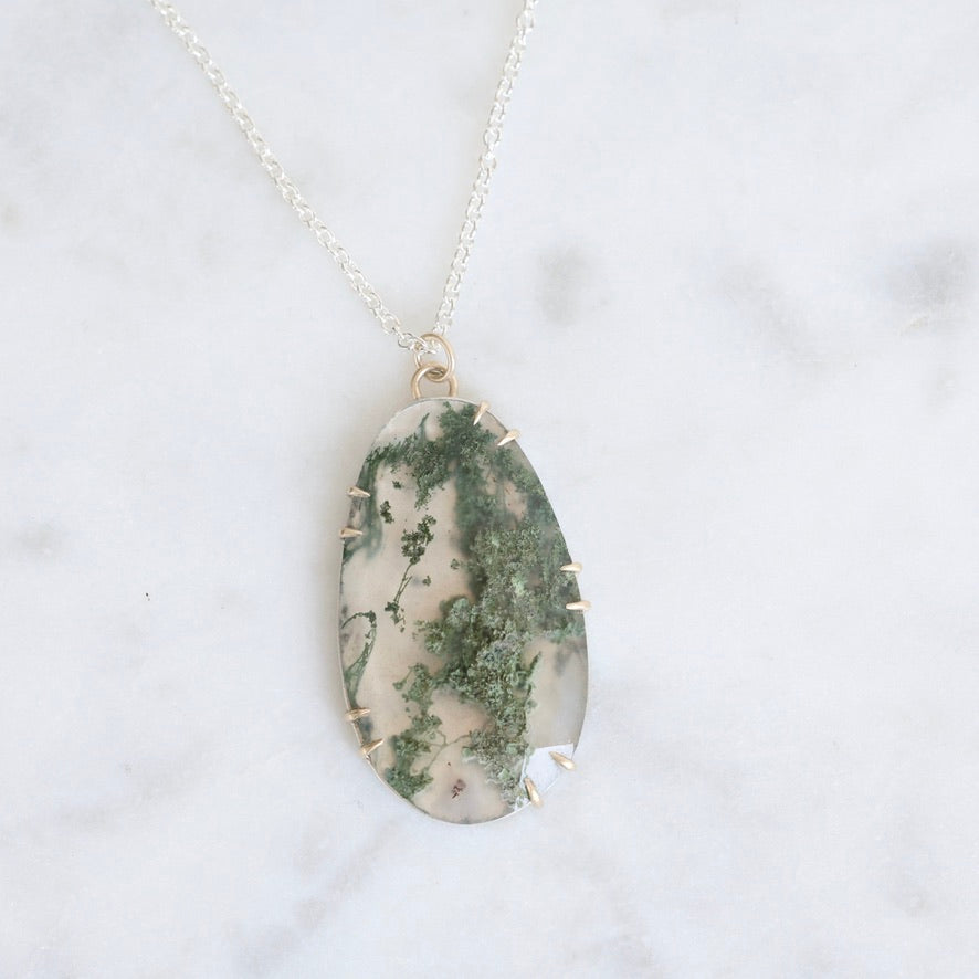 Necklace with a green and white marbled pendant on a light gray background