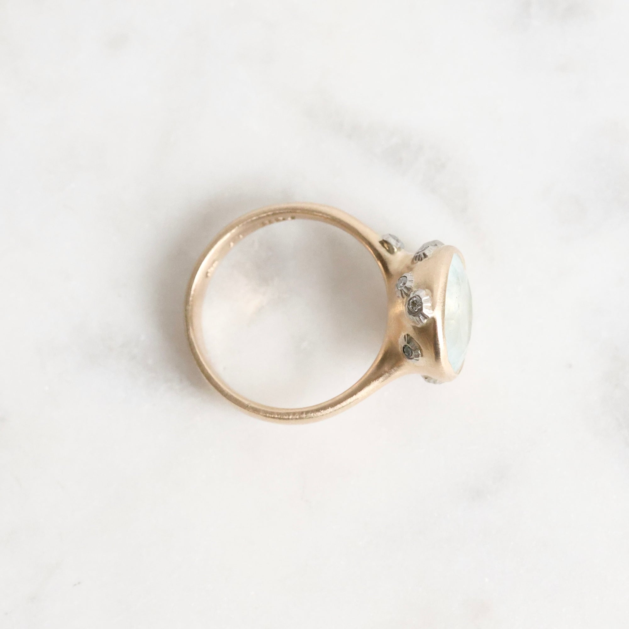 Gold ring with a large, faceted aquamarine stone on a light background