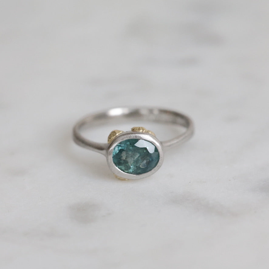 Silver ring with a green gemstone on a light gray background