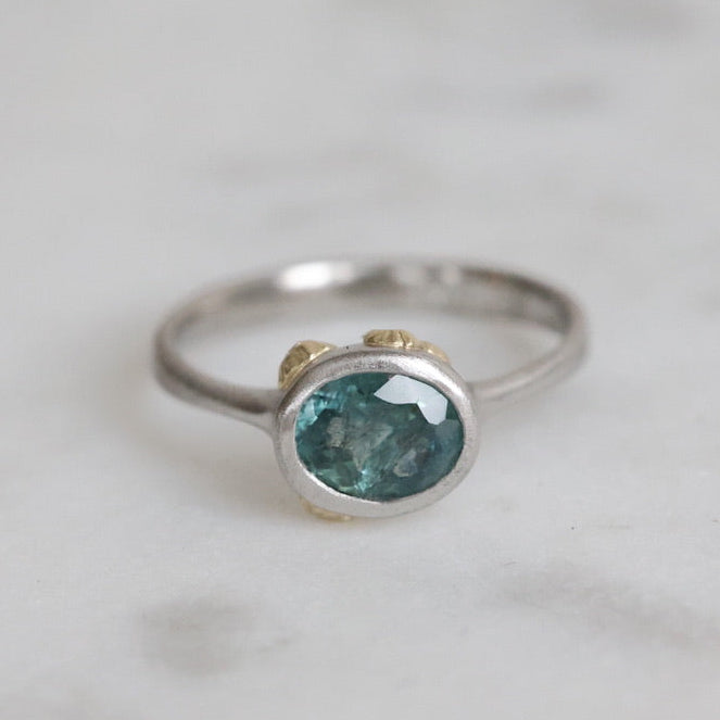 Silver ring with a blue gemstone on a light gray background