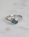 Silver ring with a green gemstone on a light gray background