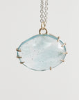 Necklace with a large round clear stone pendant on a light gray background