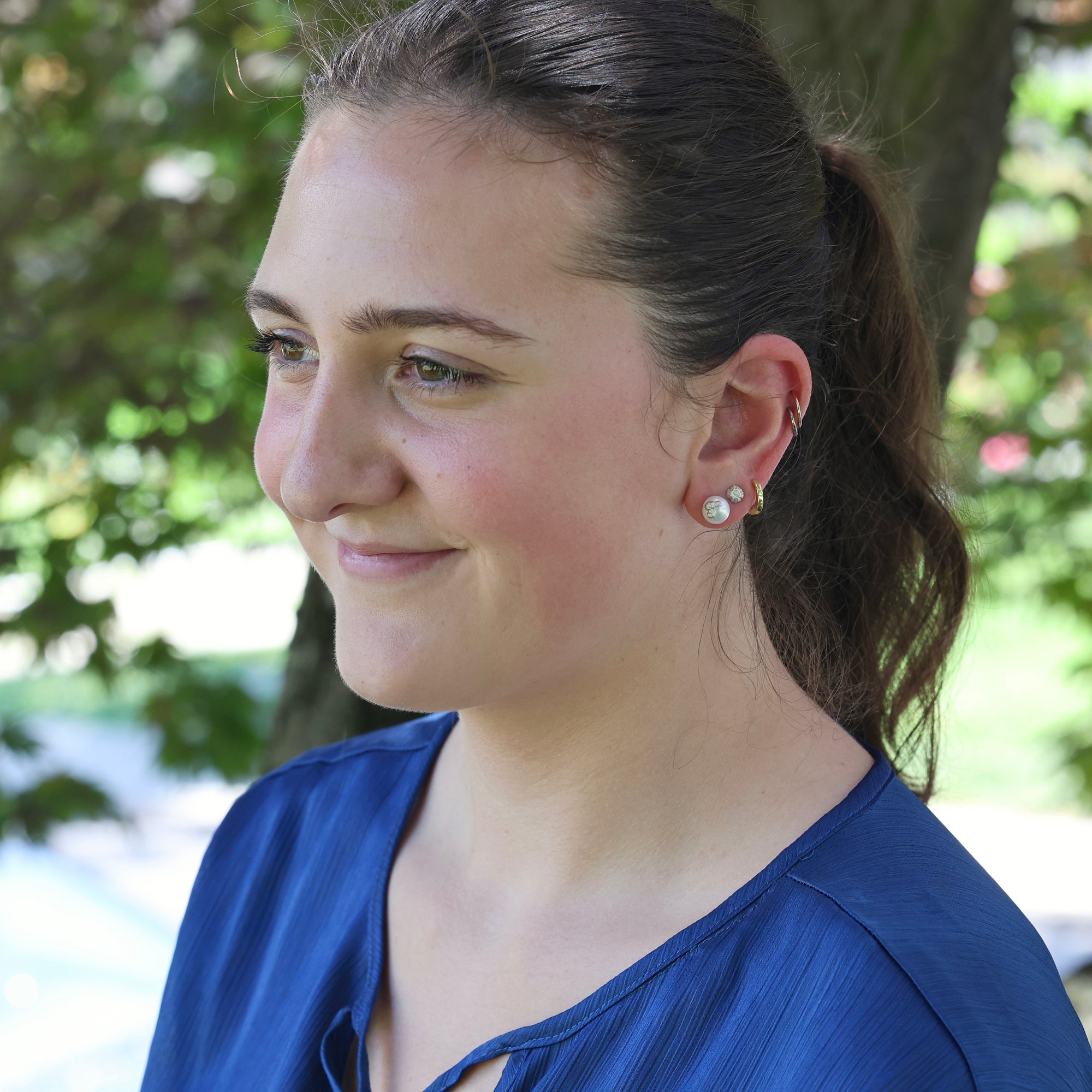 Woman wearing a blue shirt with a blurred green background