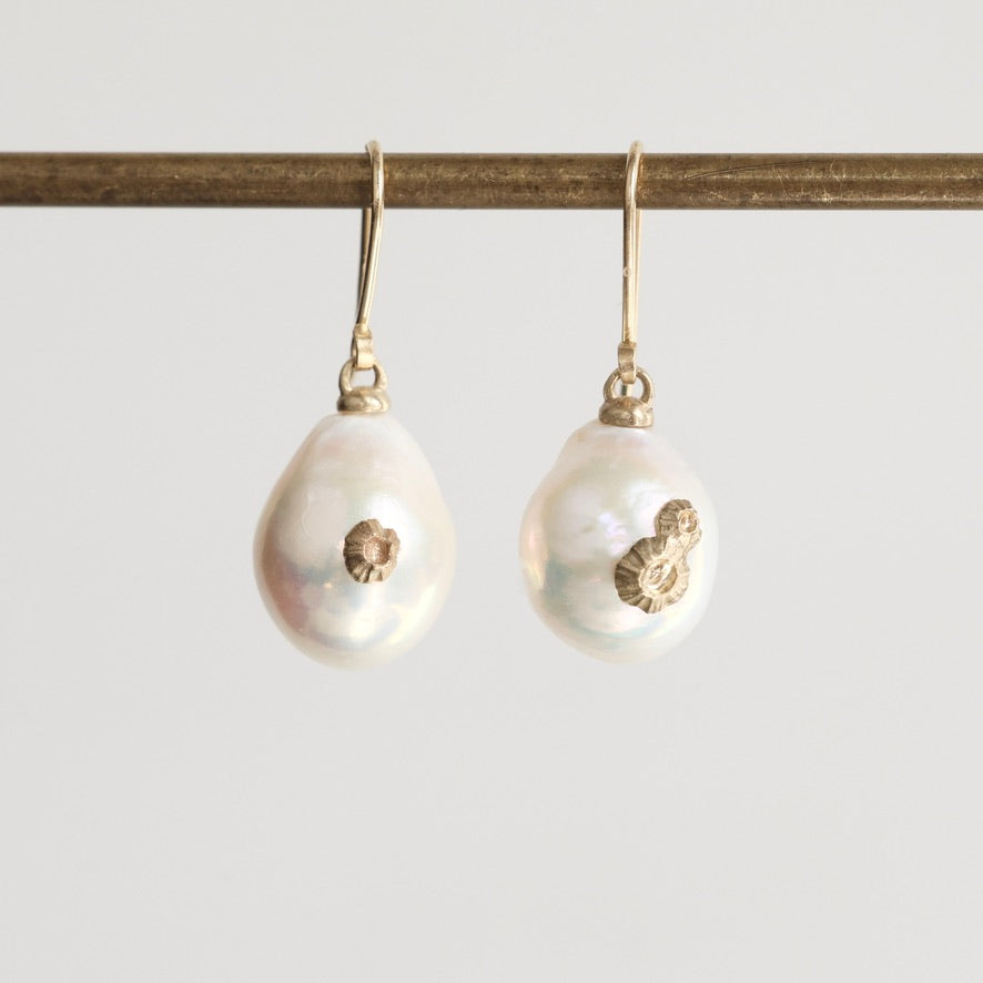 Pair of pearl earrings with gold accents on a white background