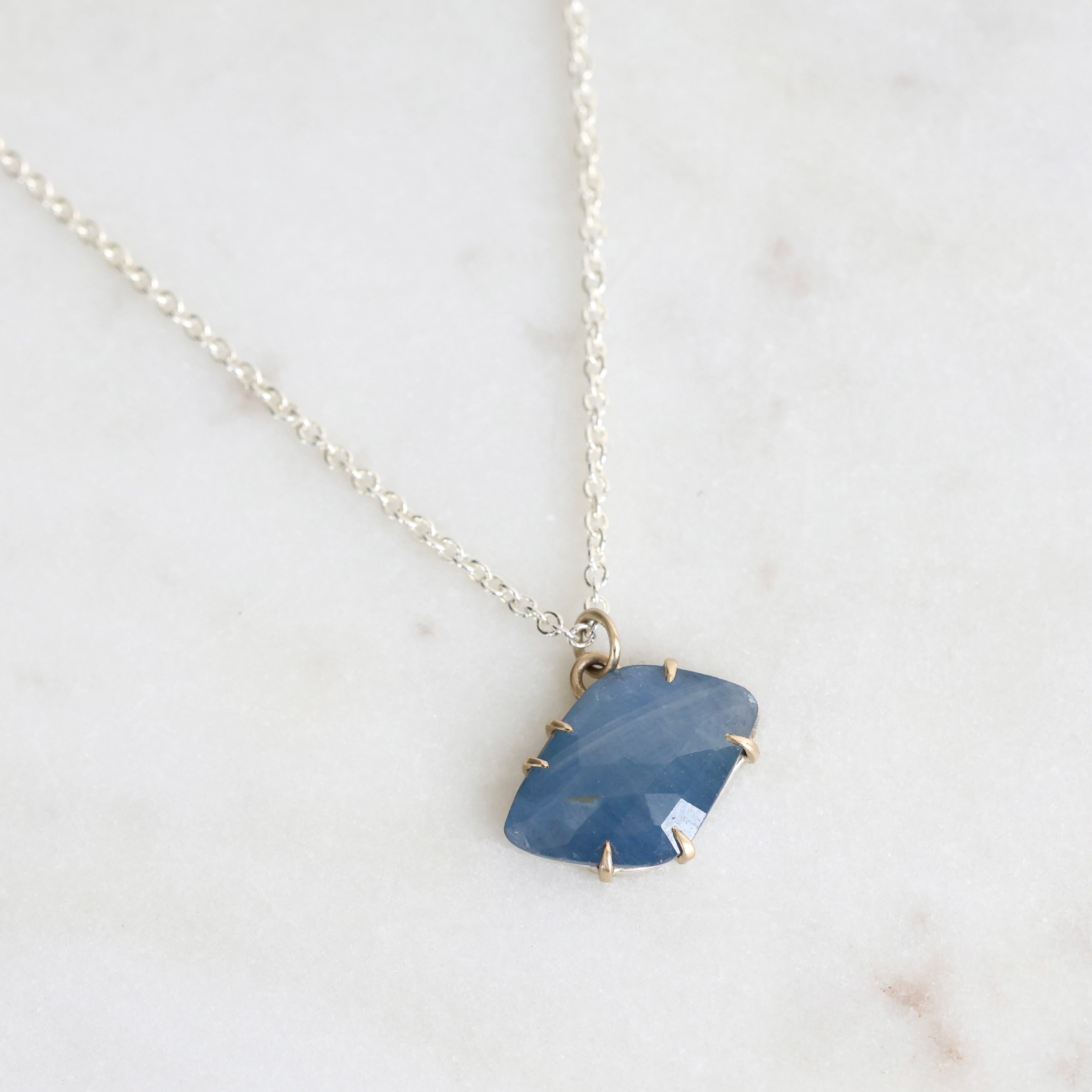 Necklace with a blue stone pendant on a light background