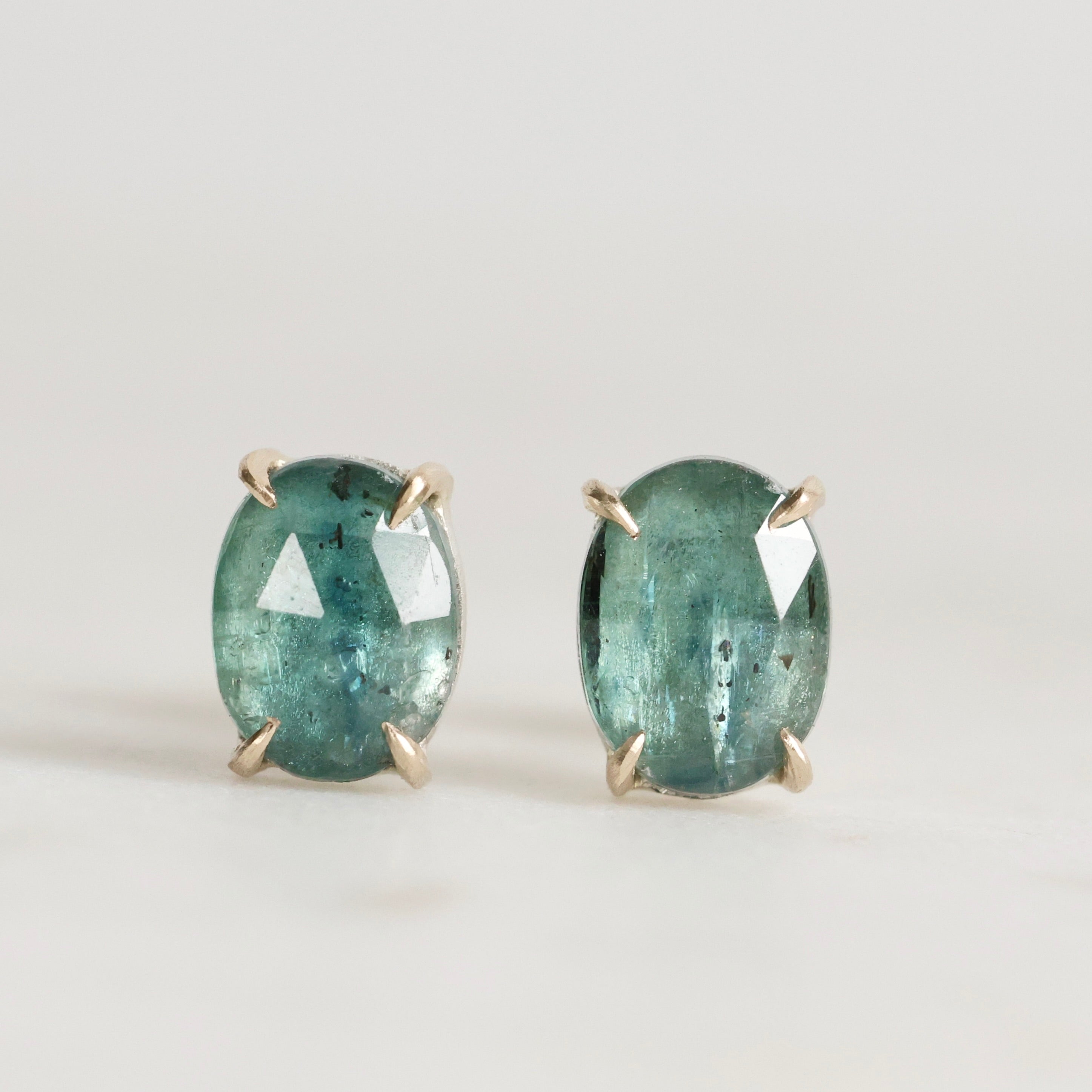 Pair of green gemstone earrings on a light gray background