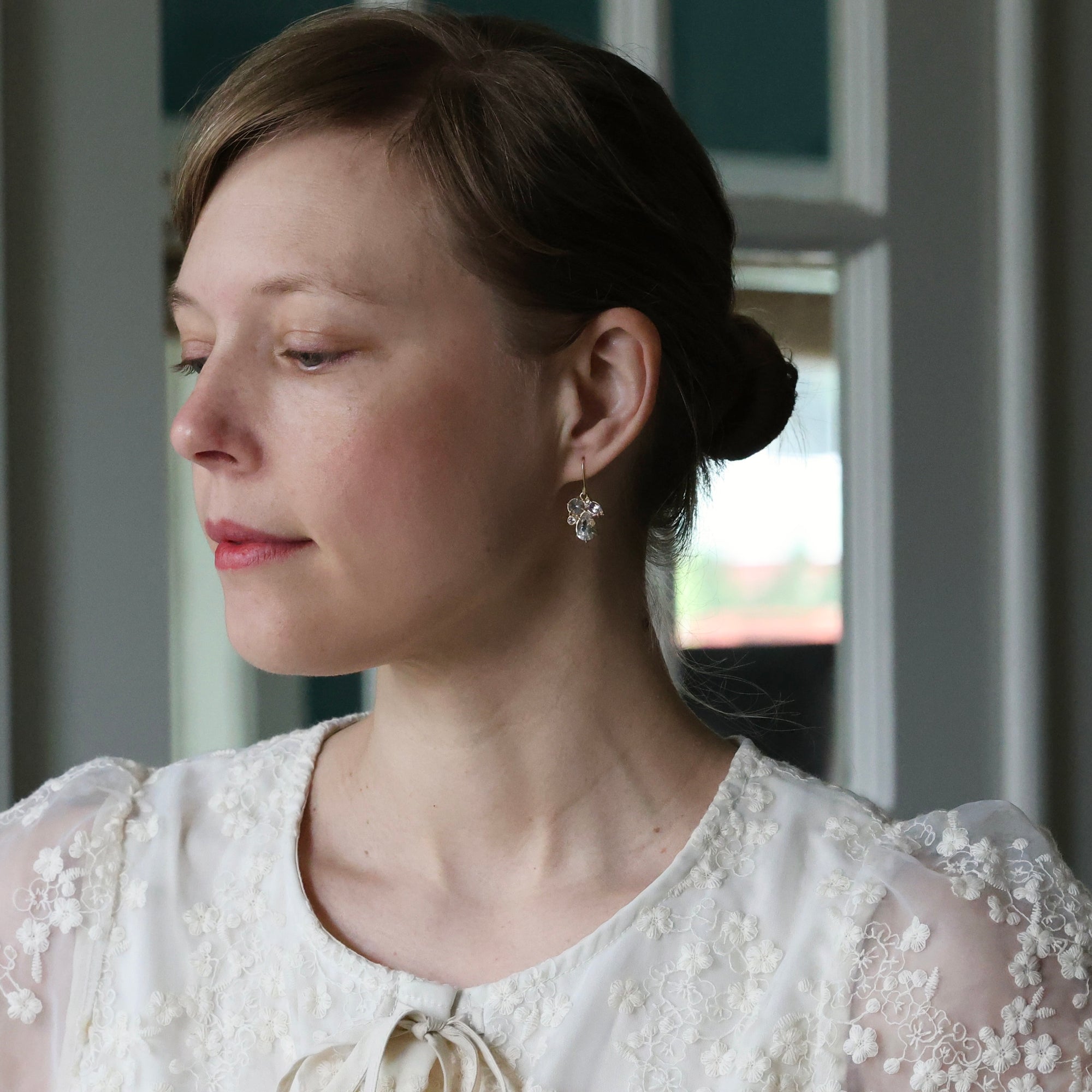 Woman wearing a white lace dress with a drop herkimer earrings