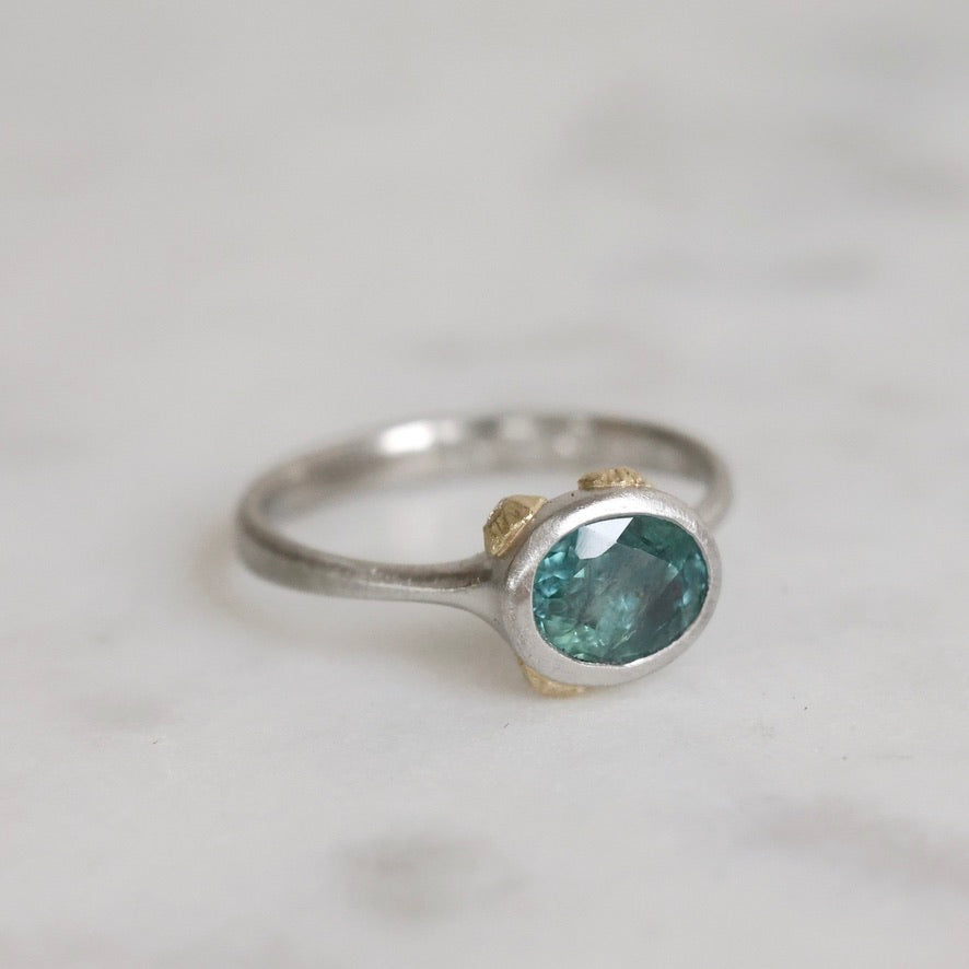 Silver ring with a green gemstone on a light gray background