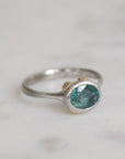 Silver ring with a green gemstone on a light gray background