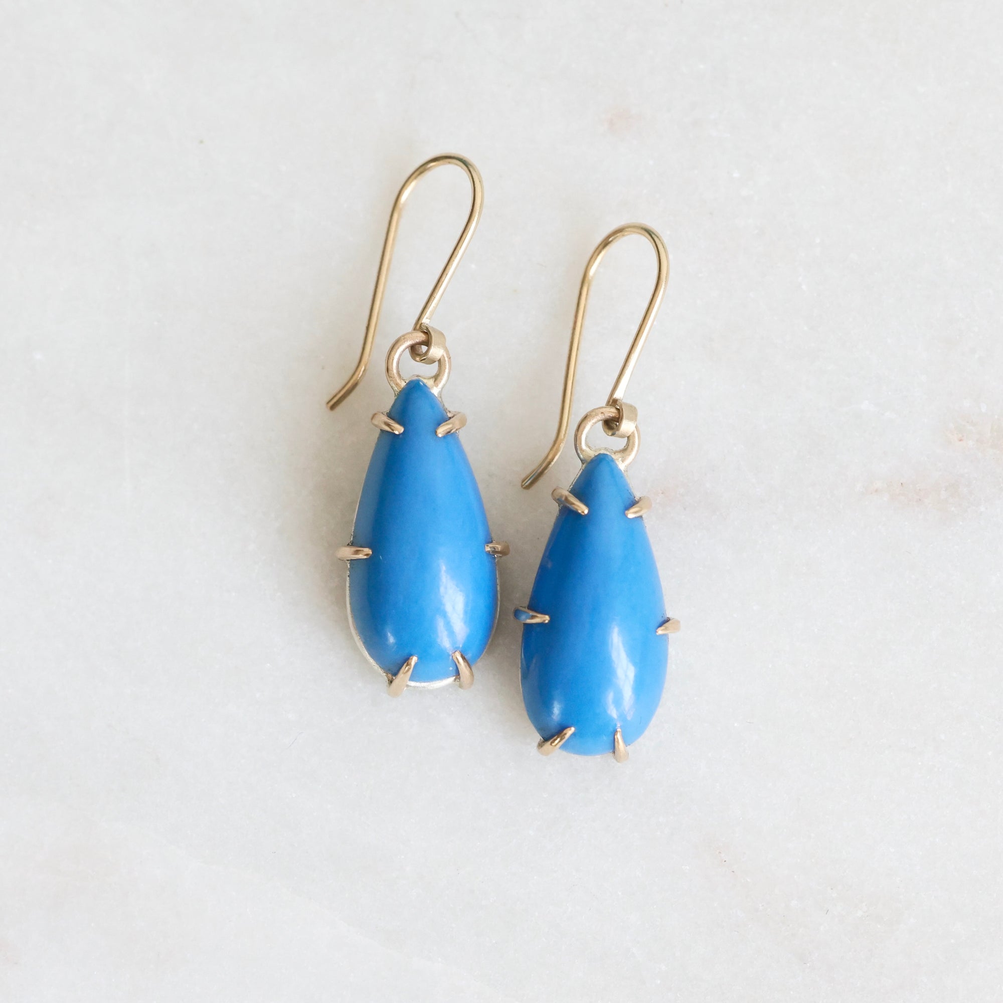 Blue teardrop earrings with gold accents on a white background