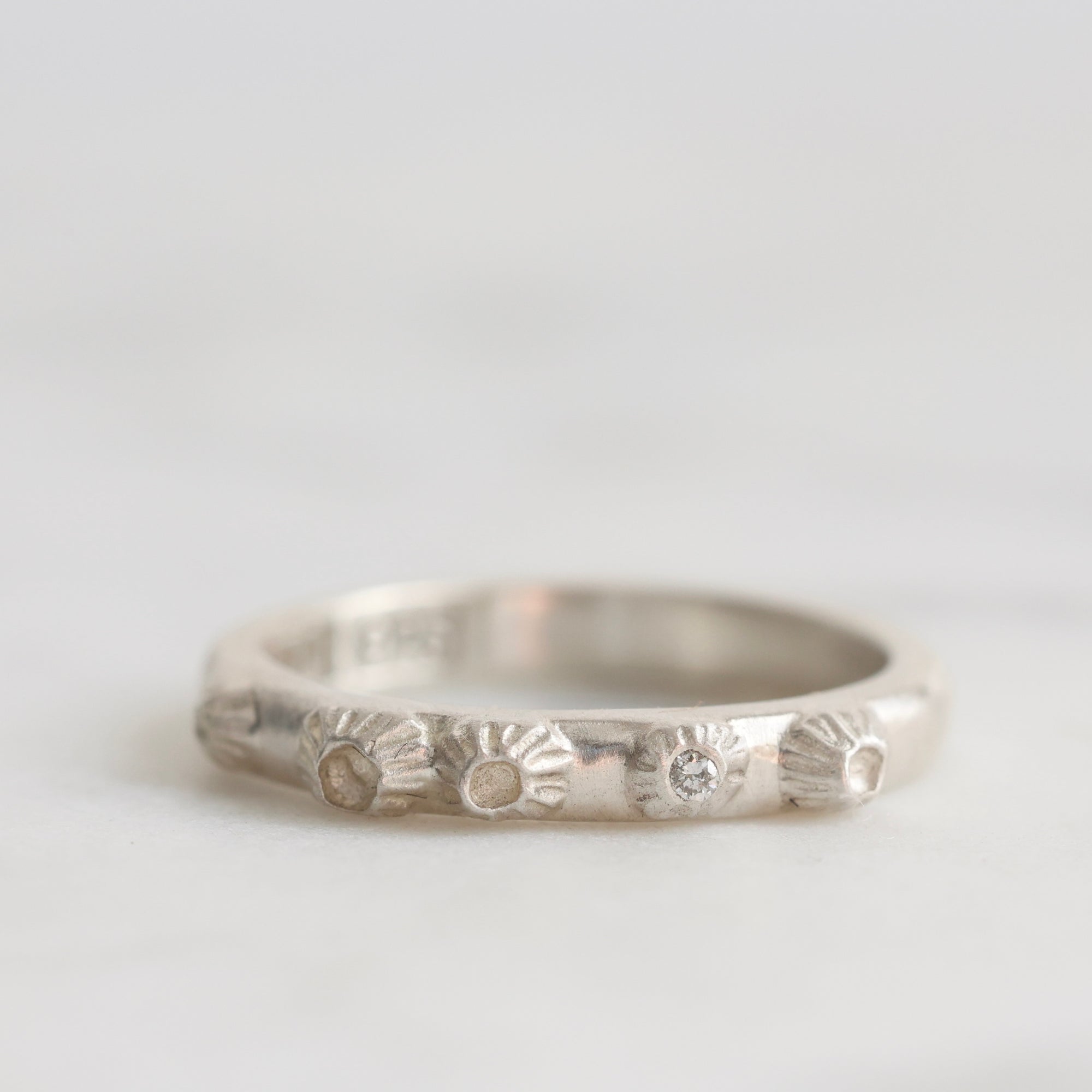 Silver ring with textured design on a light gray background
