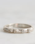Silver ring with textured design on a light gray background