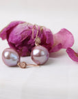 Pearl earrings with gold accents on a white background with pink flowers.