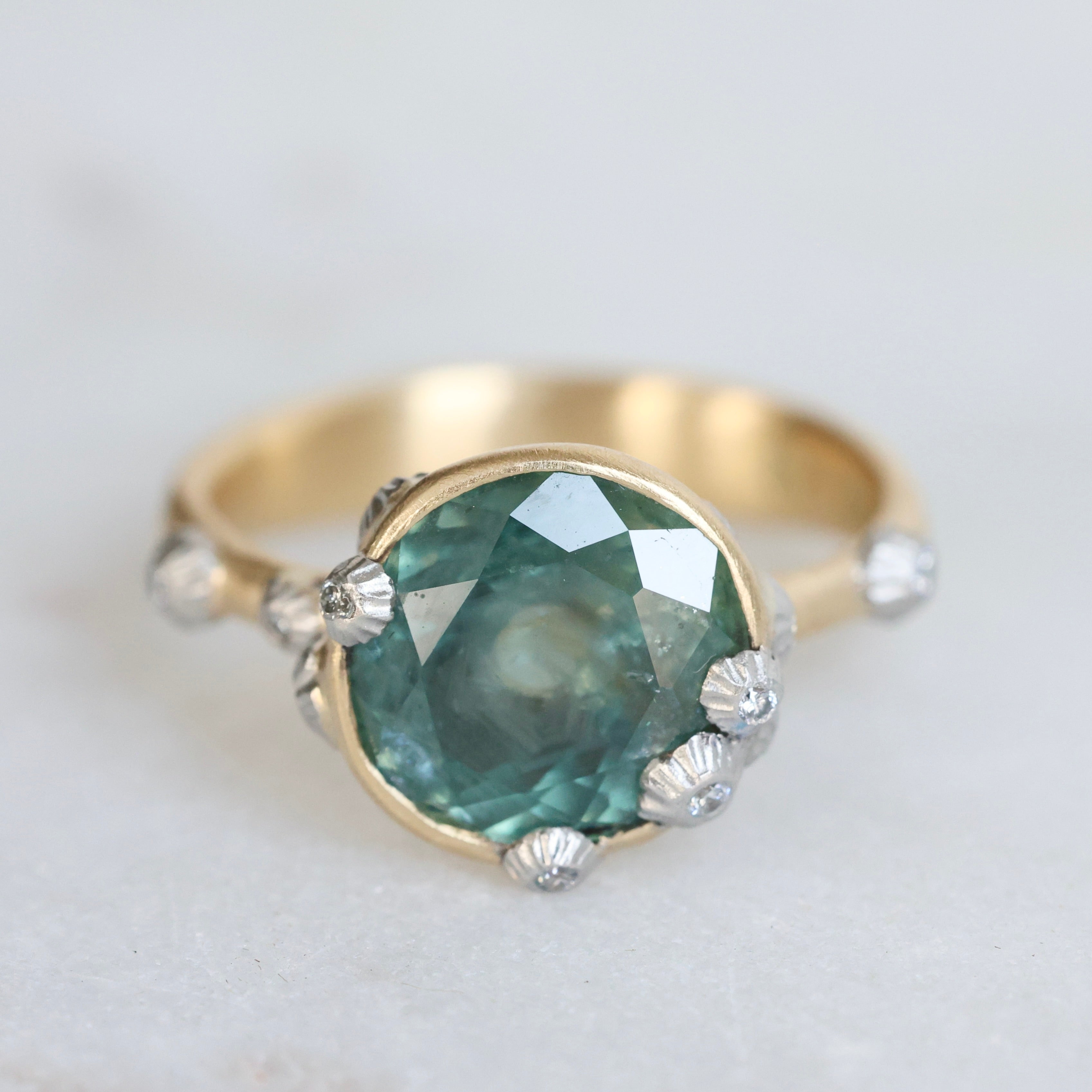 Large green sapphire ring with lots of barnacles. Gold shank