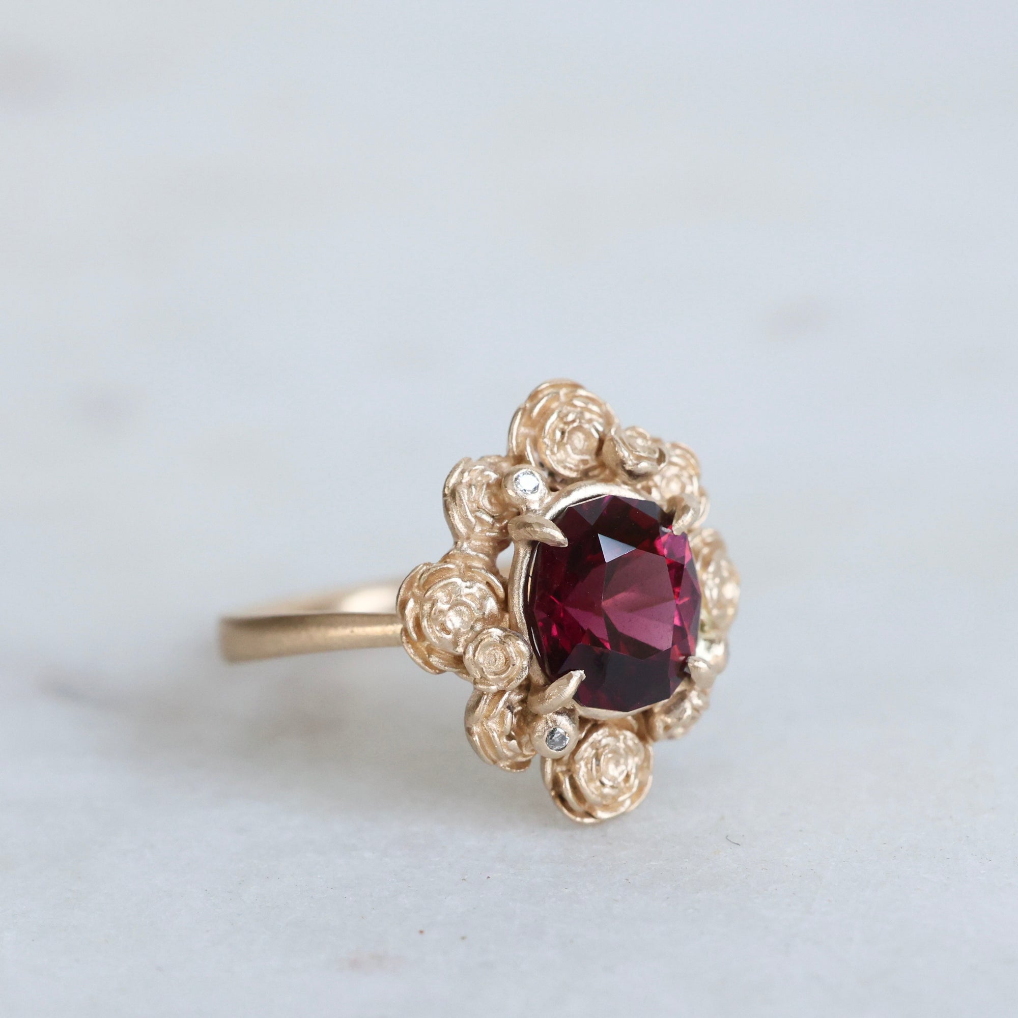Gold ring with a red gemstone on a light gray background
