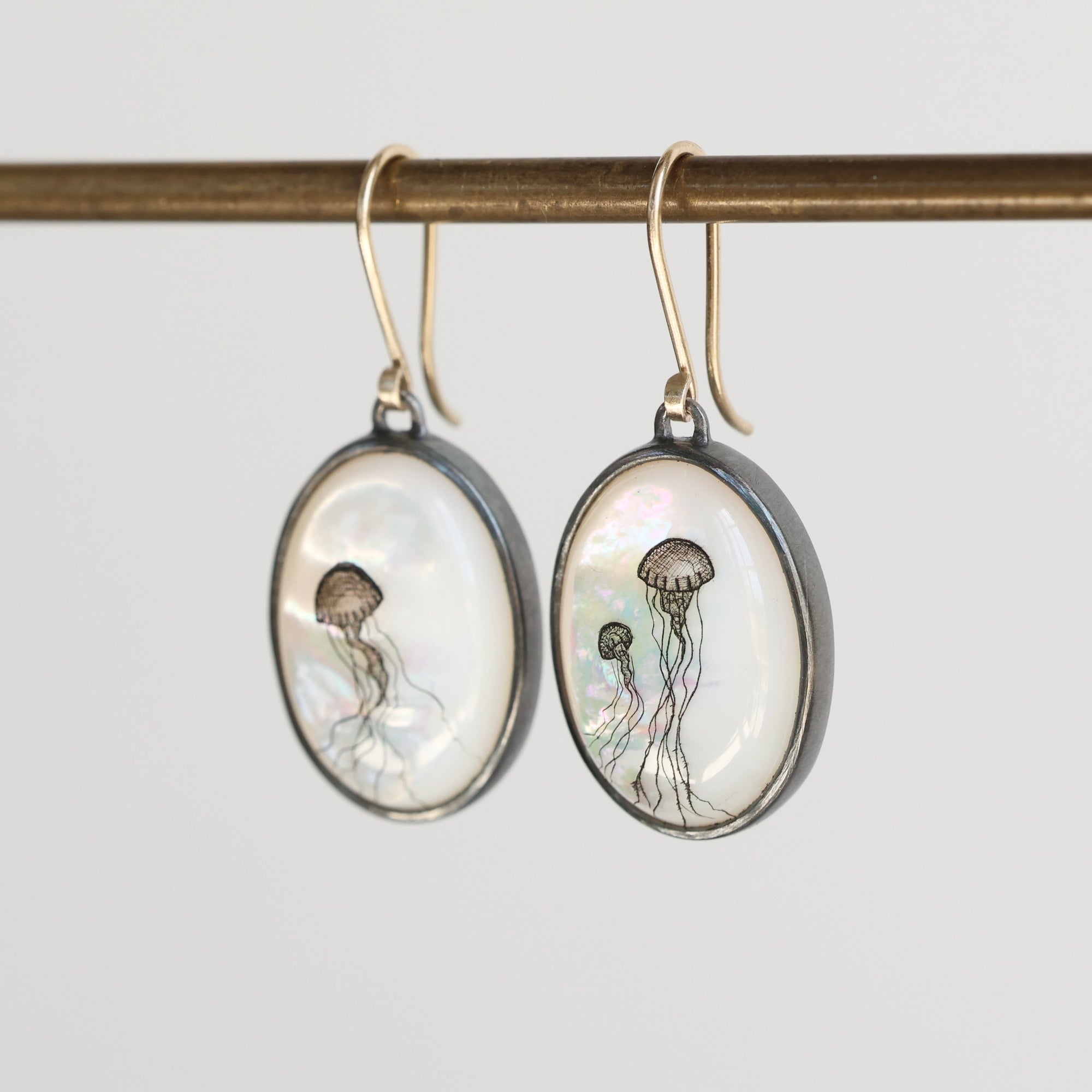 Oval-shaped earrings with jellyfish design on a white background