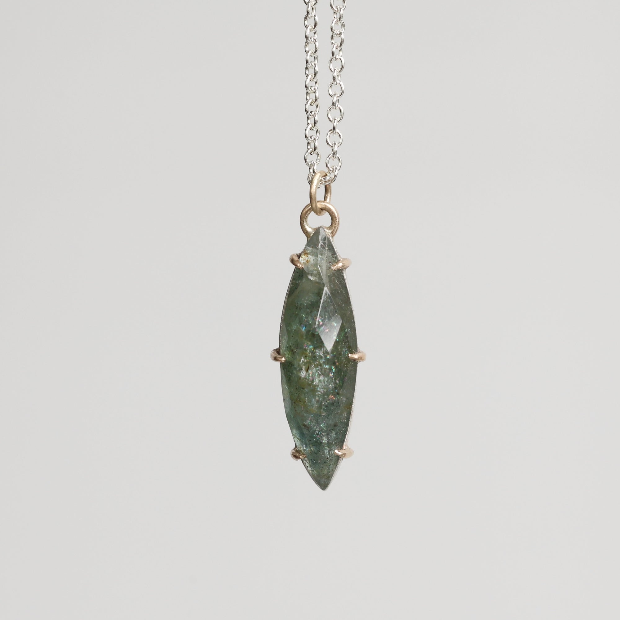 Necklace with a green stone pendant on a light gray background