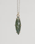 Necklace with a green stone pendant on a light gray background