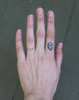 Hand with a ring and tattoo on a dark background