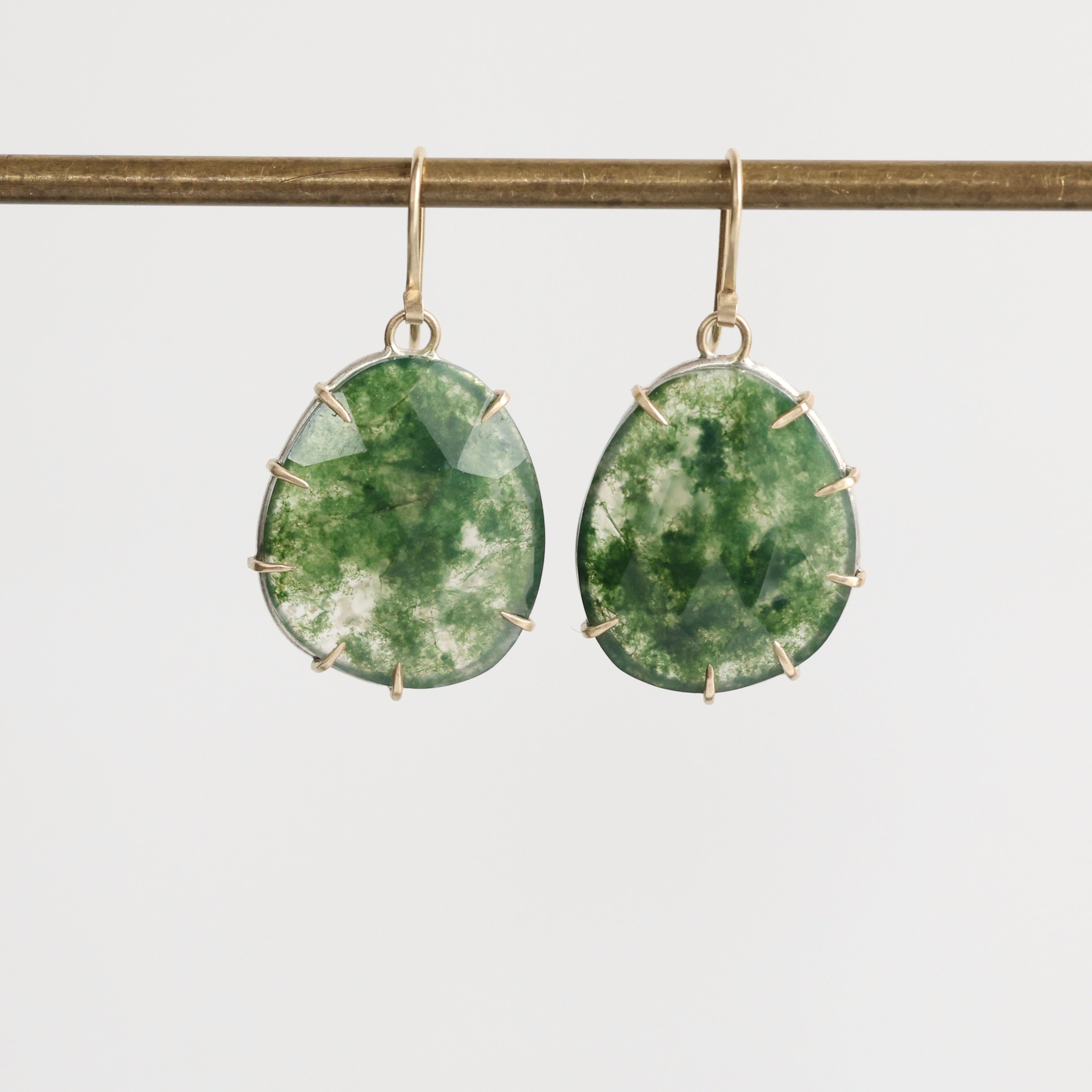 Green stone earrings with gold accents on a white background