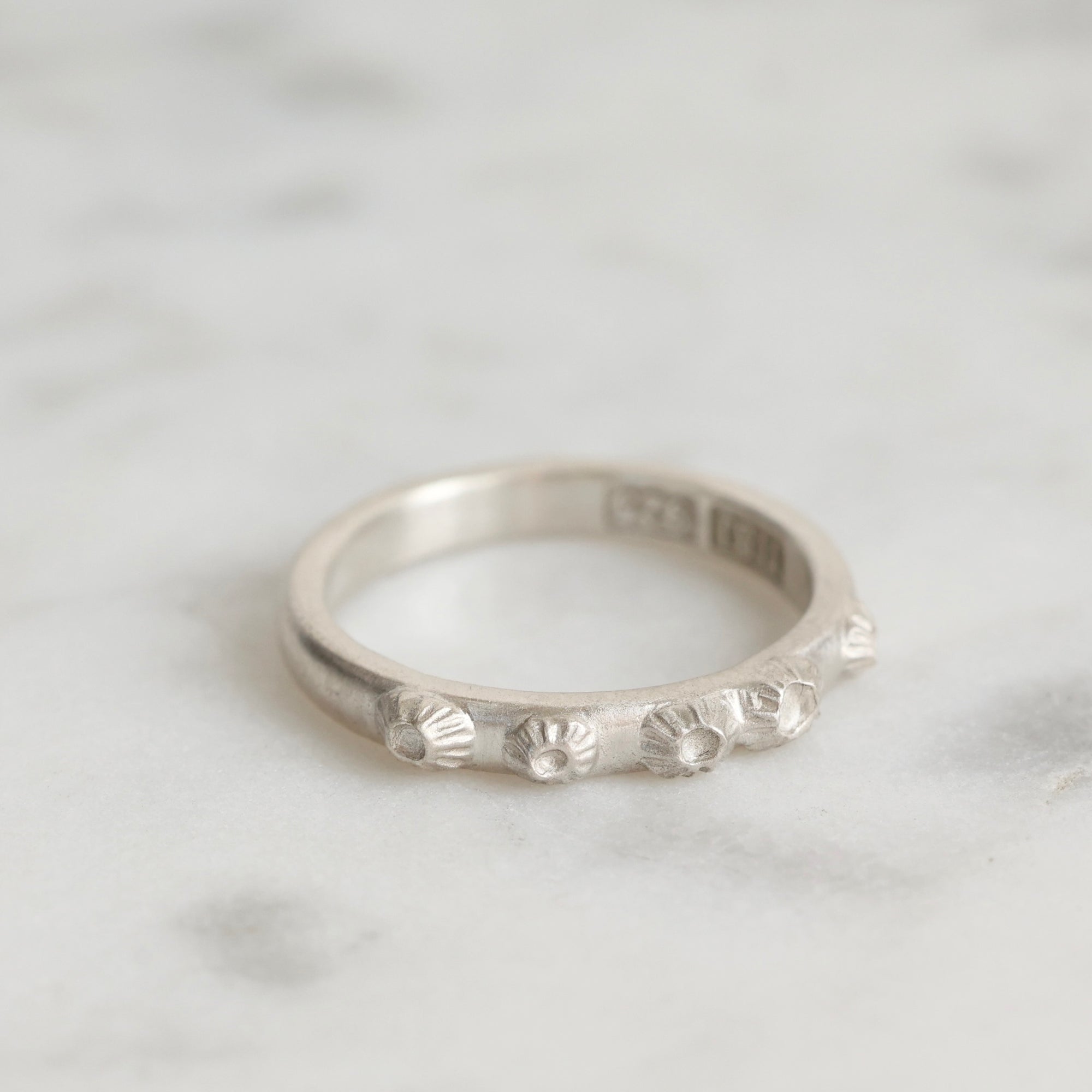 Silver ring with barnacle design on a light gray background